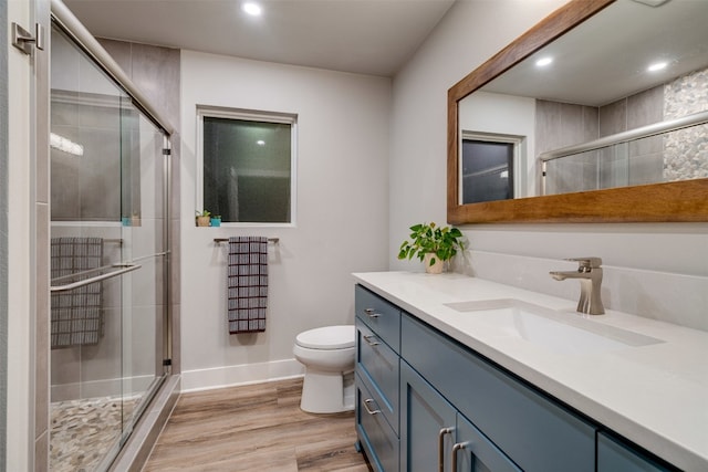 bathroom featuring an enclosed shower, oversized vanity, toilet, and wood-type flooring