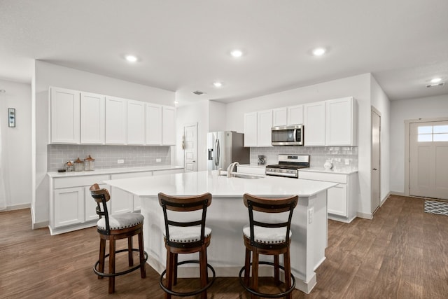 kitchen featuring a kitchen breakfast bar, white cabinetry, dark hardwood / wood-style floors, and stainless steel appliances