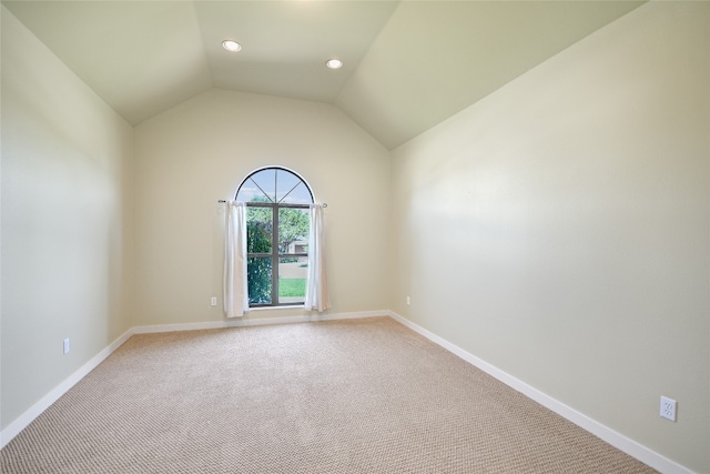 carpeted empty room featuring vaulted ceiling