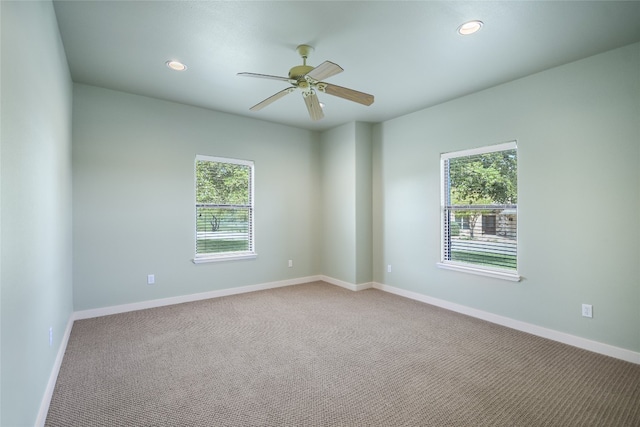 carpeted spare room with ceiling fan and plenty of natural light