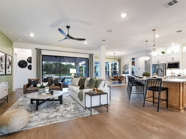 living room with ceiling fan with notable chandelier, dark hardwood / wood-style floors, and sink