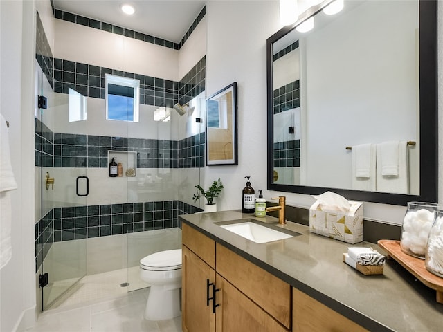 bathroom with tile flooring, vanity, toilet, and a shower with shower door