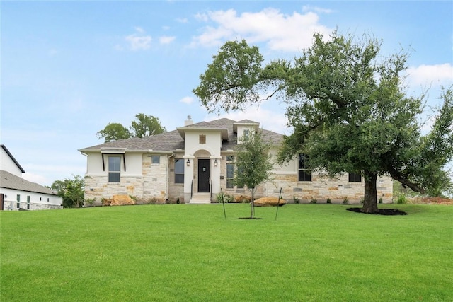 view of front of home with stone siding, a chimney, a front lawn, and stucco siding