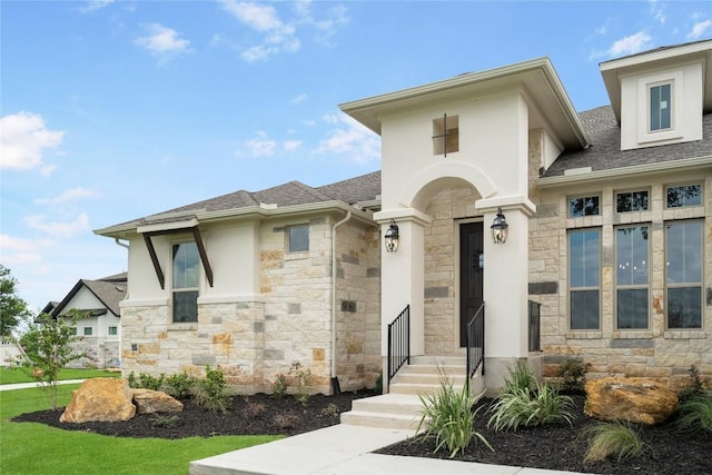 view of front facade featuring stone siding, roof with shingles, and stucco siding