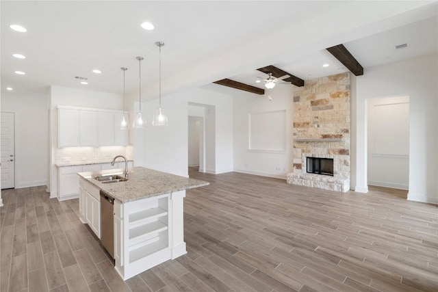 kitchen with wood finish floors, a fireplace, dishwasher, and a sink