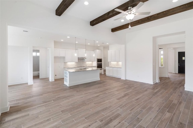 unfurnished living room with light wood-type flooring, ceiling fan, beam ceiling, and recessed lighting