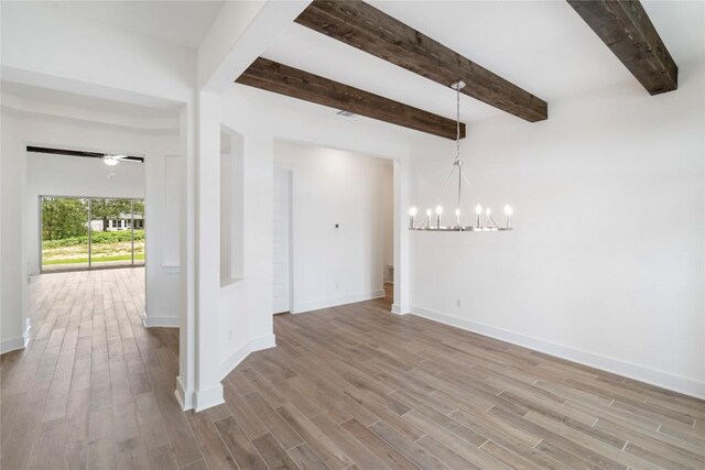 spare room featuring ceiling fan with notable chandelier, wood finished floors, beam ceiling, and baseboards