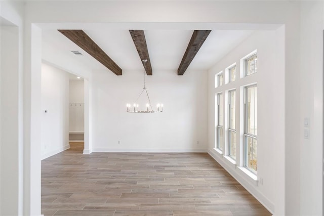 spare room featuring an inviting chandelier, light wood-style flooring, baseboards, and beamed ceiling