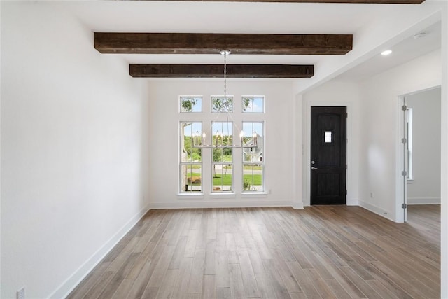 foyer entrance featuring light wood-type flooring, beam ceiling, and baseboards