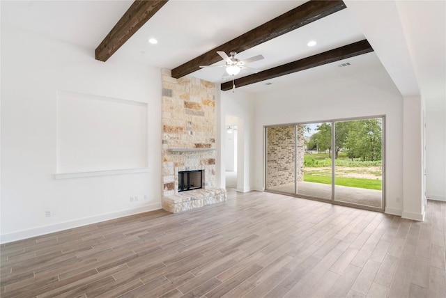 unfurnished living room featuring visible vents, a ceiling fan, a stone fireplace, wood finished floors, and baseboards