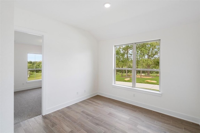 unfurnished room featuring lofted ceiling, wood finished floors, and baseboards