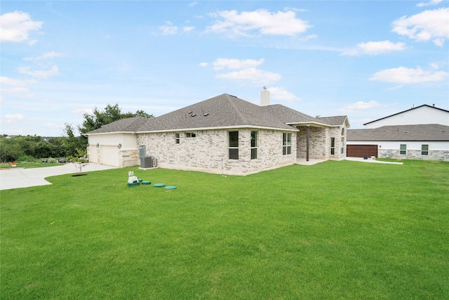 back of property with a garage, a lawn, and central AC unit