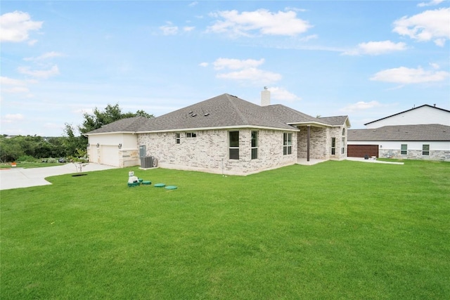 rear view of property featuring a chimney, concrete driveway, a lawn, an attached garage, and cooling unit