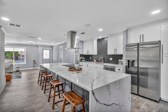 kitchen with a kitchen island, white cabinetry, stainless steel appliances, light hardwood / wood-style flooring, and island exhaust hood