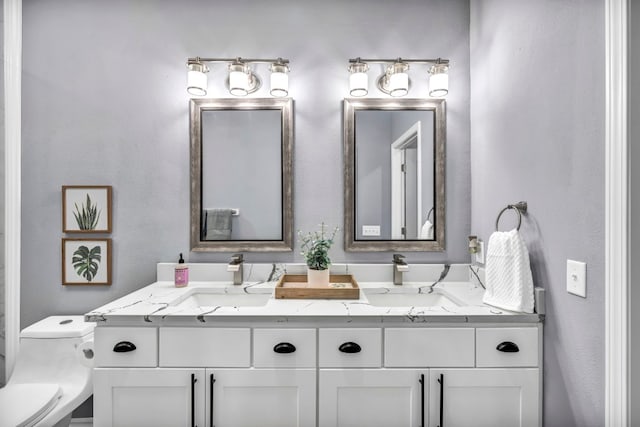 bathroom featuring toilet and dual vanity