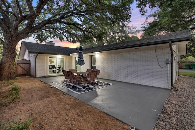 back house at dusk featuring a patio