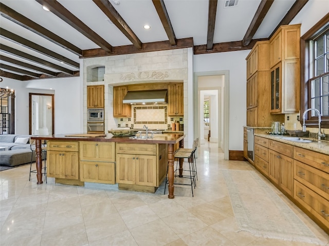 kitchen featuring light tile flooring, a notable chandelier, a kitchen bar, sink, and beam ceiling