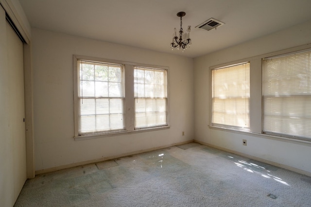 carpeted empty room featuring an inviting chandelier