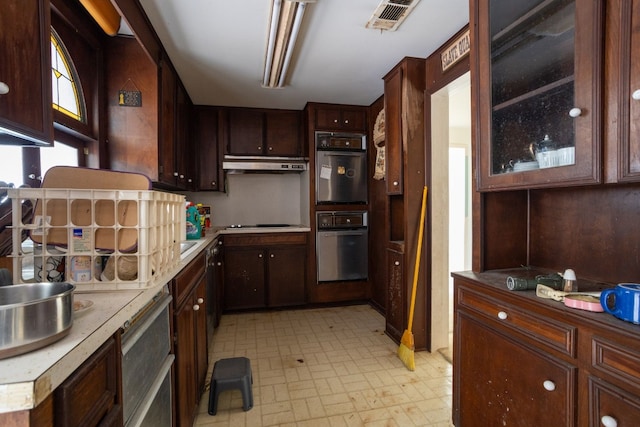 kitchen with stainless steel gas stovetop, dark brown cabinets, and black double oven