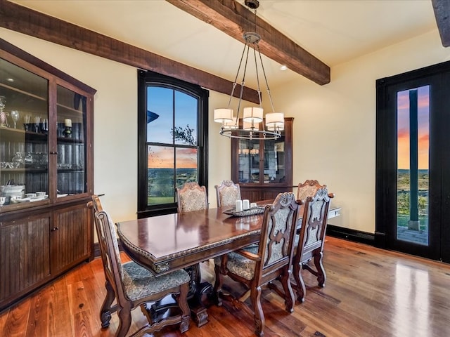 dining space featuring beamed ceiling, a chandelier, and light hardwood / wood-style flooring