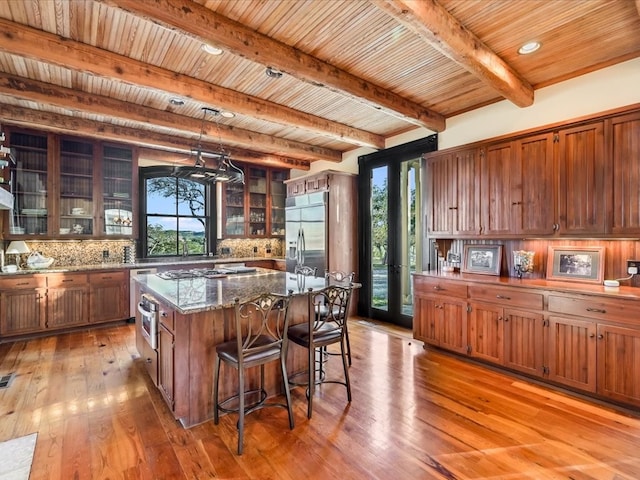 kitchen with a center island, beam ceiling, a wealth of natural light, and appliances with stainless steel finishes