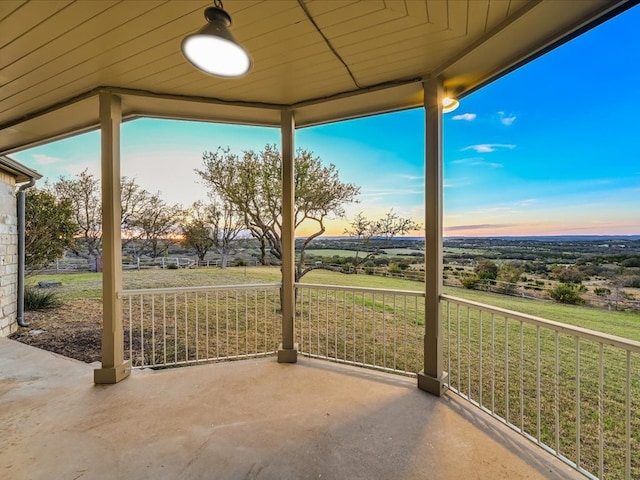 patio terrace at dusk with a rural view and a lawn