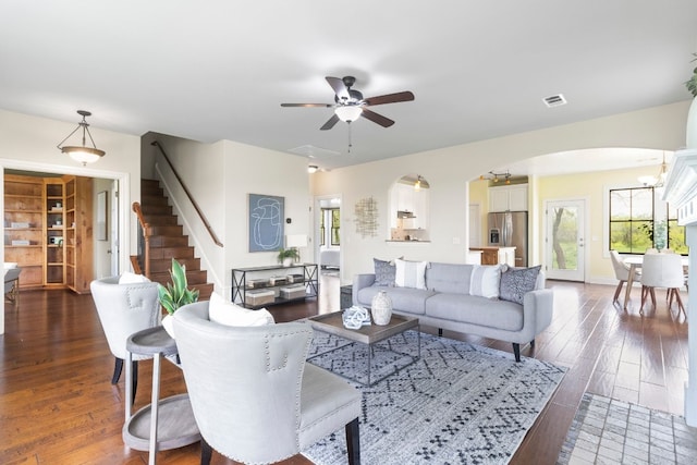 living room featuring ceiling fan with notable chandelier and dark hardwood / wood-style flooring