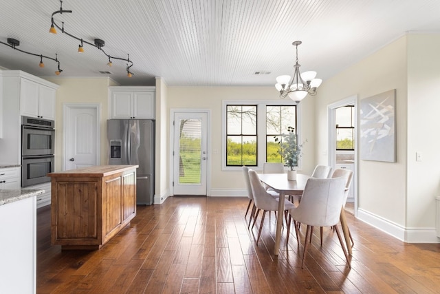 kitchen with dark wood-type flooring, appliances with stainless steel finishes, hanging light fixtures, and white cabinetry