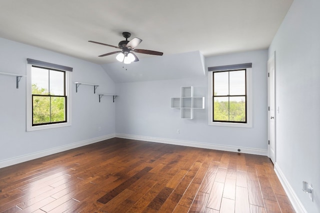 unfurnished room with vaulted ceiling, a wealth of natural light, and dark hardwood / wood-style flooring