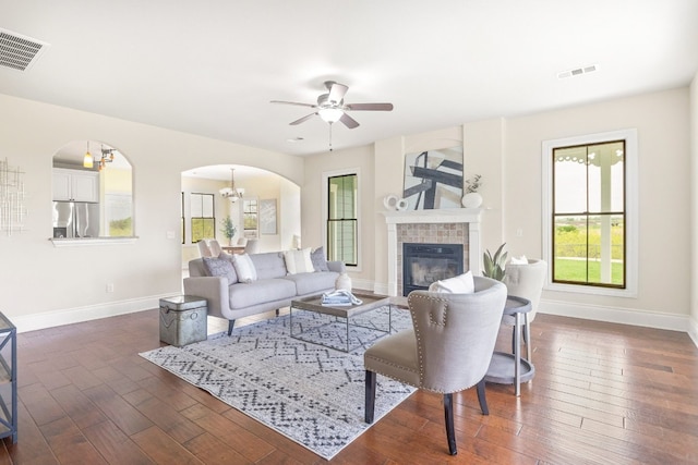 living room featuring a fireplace, dark hardwood / wood-style floors, and ceiling fan with notable chandelier