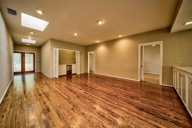 empty room with french doors, a skylight, and hardwood / wood-style flooring