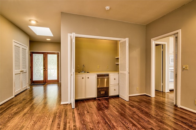 interior space with sink, dark wood-type flooring, white cabinetry, a skylight, and french doors