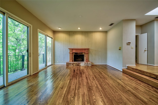 unfurnished living room with wooden walls, wood-type flooring, and a fireplace