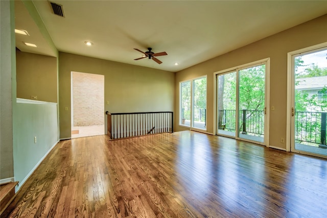 unfurnished room with ceiling fan, wood-type flooring, and a wealth of natural light