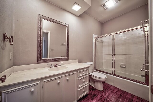 full bathroom featuring vanity, wood-type flooring, shower / bath combination with glass door, and toilet