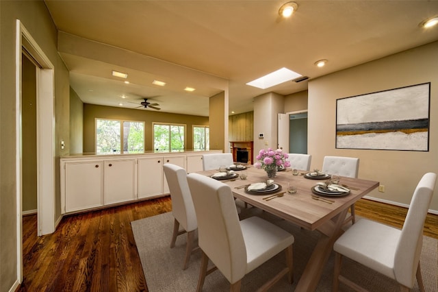 dining space featuring dark hardwood / wood-style floors, ceiling fan, and a skylight