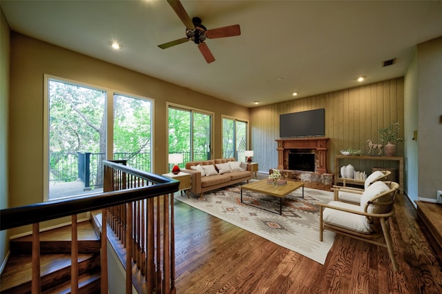 living room with ceiling fan, hardwood / wood-style floors, and wood walls