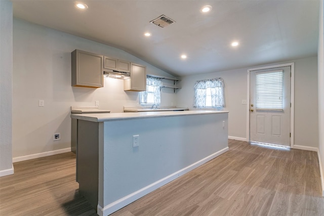 kitchen with a kitchen island, light hardwood / wood-style floors, vaulted ceiling, sink, and gray cabinetry