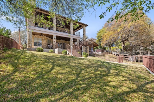 rear view of property featuring ceiling fan and a yard