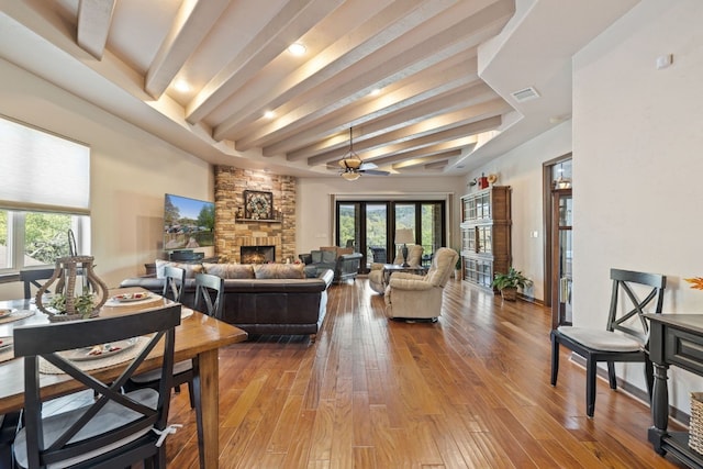 living room with hardwood / wood-style floors, a fireplace, ceiling fan, and beamed ceiling