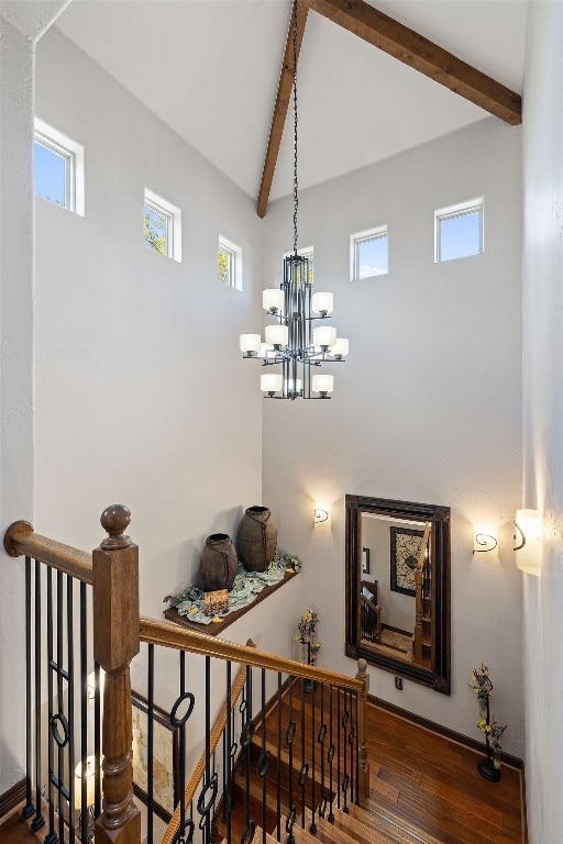 stairs featuring a notable chandelier, dark hardwood / wood-style flooring, a wealth of natural light, and lofted ceiling with beams