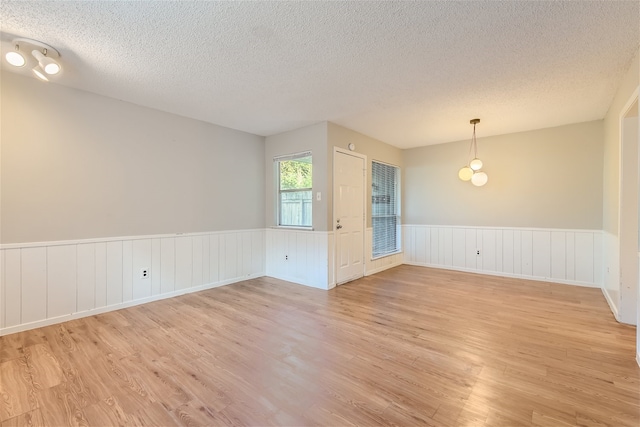 empty room featuring a textured ceiling and light hardwood / wood-style floors