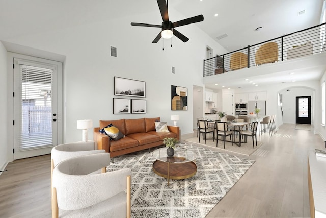 living room featuring high vaulted ceiling, light hardwood / wood-style floors, and ceiling fan