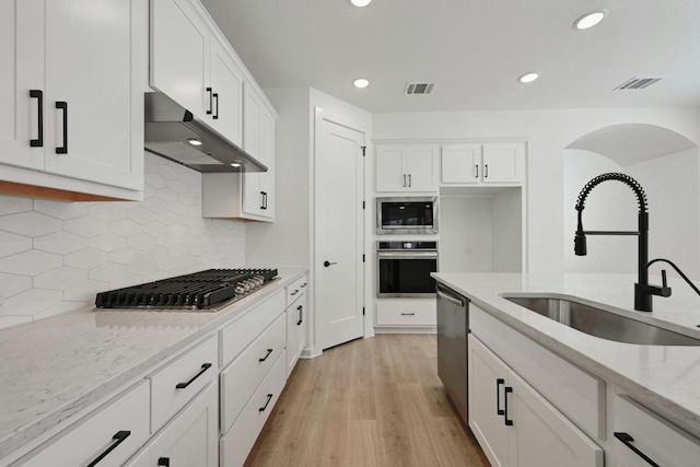 kitchen featuring light hardwood / wood-style flooring, light stone counters, appliances with stainless steel finishes, and sink