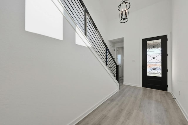 entrance foyer with light wood-type flooring, a chandelier, and a high ceiling