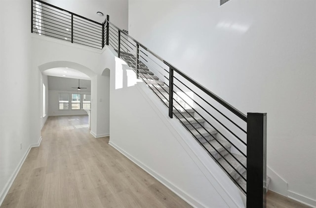 stairway with wood-type flooring and a high ceiling