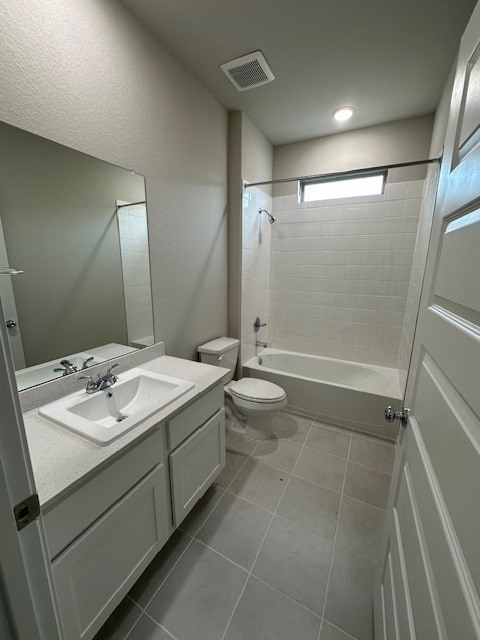 full bathroom with tile patterned floors, tiled shower / bath combo, vanity, and toilet