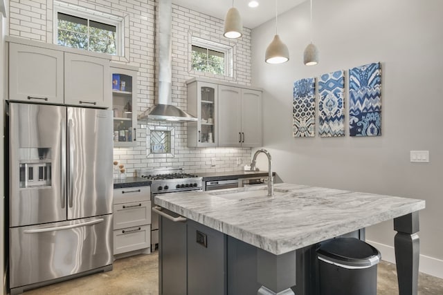 kitchen with a healthy amount of sunlight, tasteful backsplash, an island with sink, appliances with stainless steel finishes, and pendant lighting