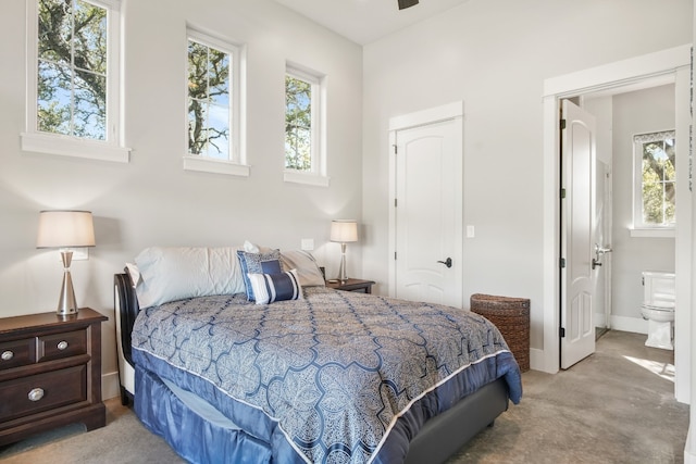 carpeted bedroom featuring ensuite bathroom and multiple windows