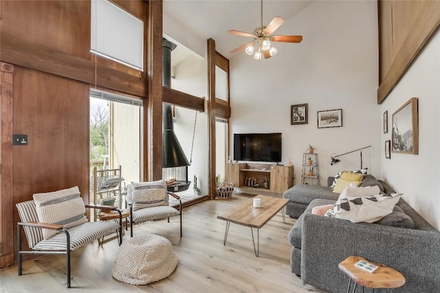 living room featuring ceiling fan, high vaulted ceiling, and light hardwood / wood-style flooring